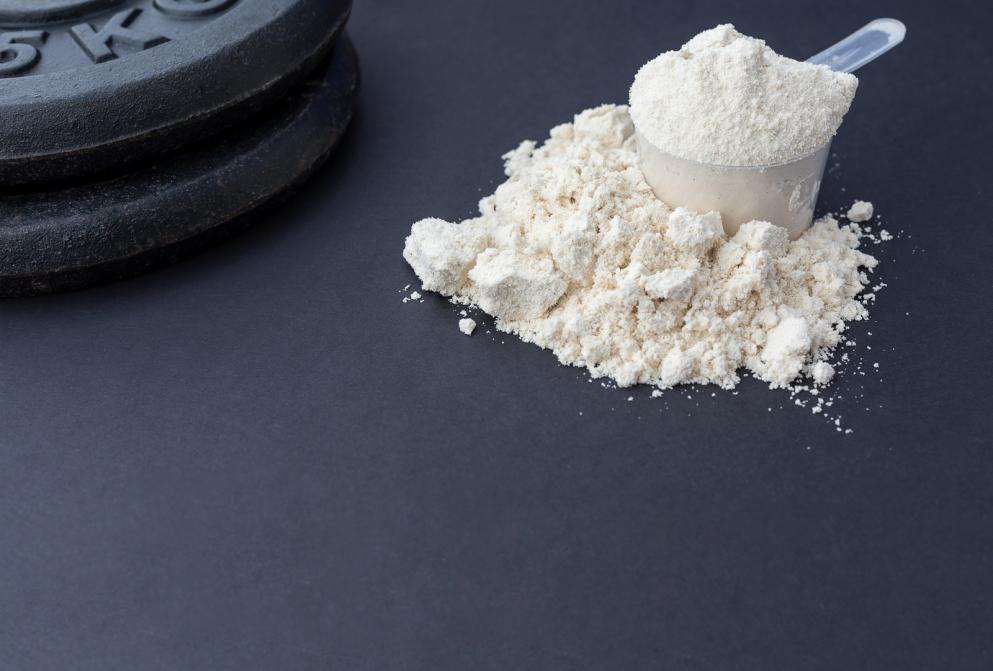 protein powder on dark with weights plates